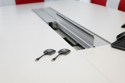 Konferenztisch mit Strom- und Datenanschlüsse bündig unter Kabelklappen eingearbeitet